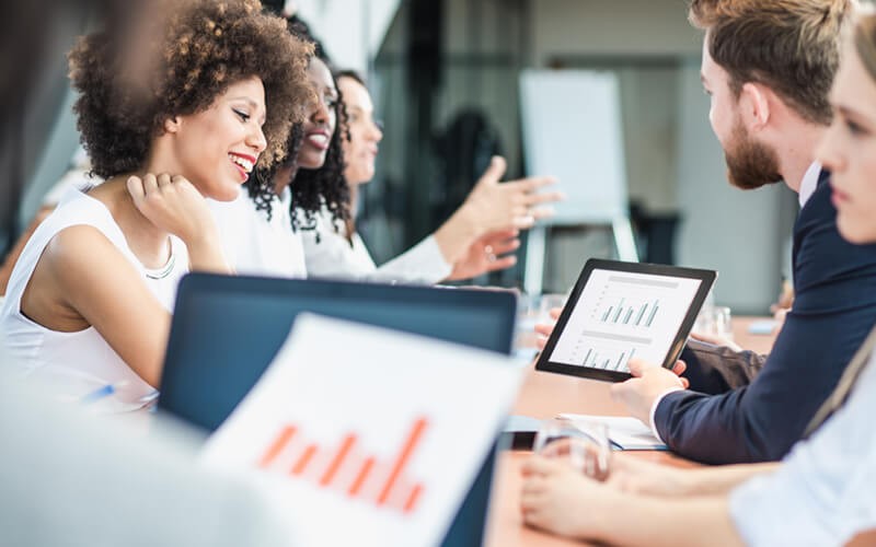 Smiling analysts gather together with reports and data